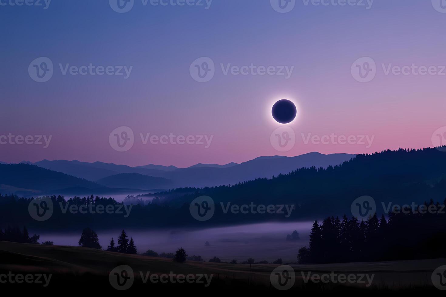 Total solar eclipse occurring over misty mountain valley at dawn photo