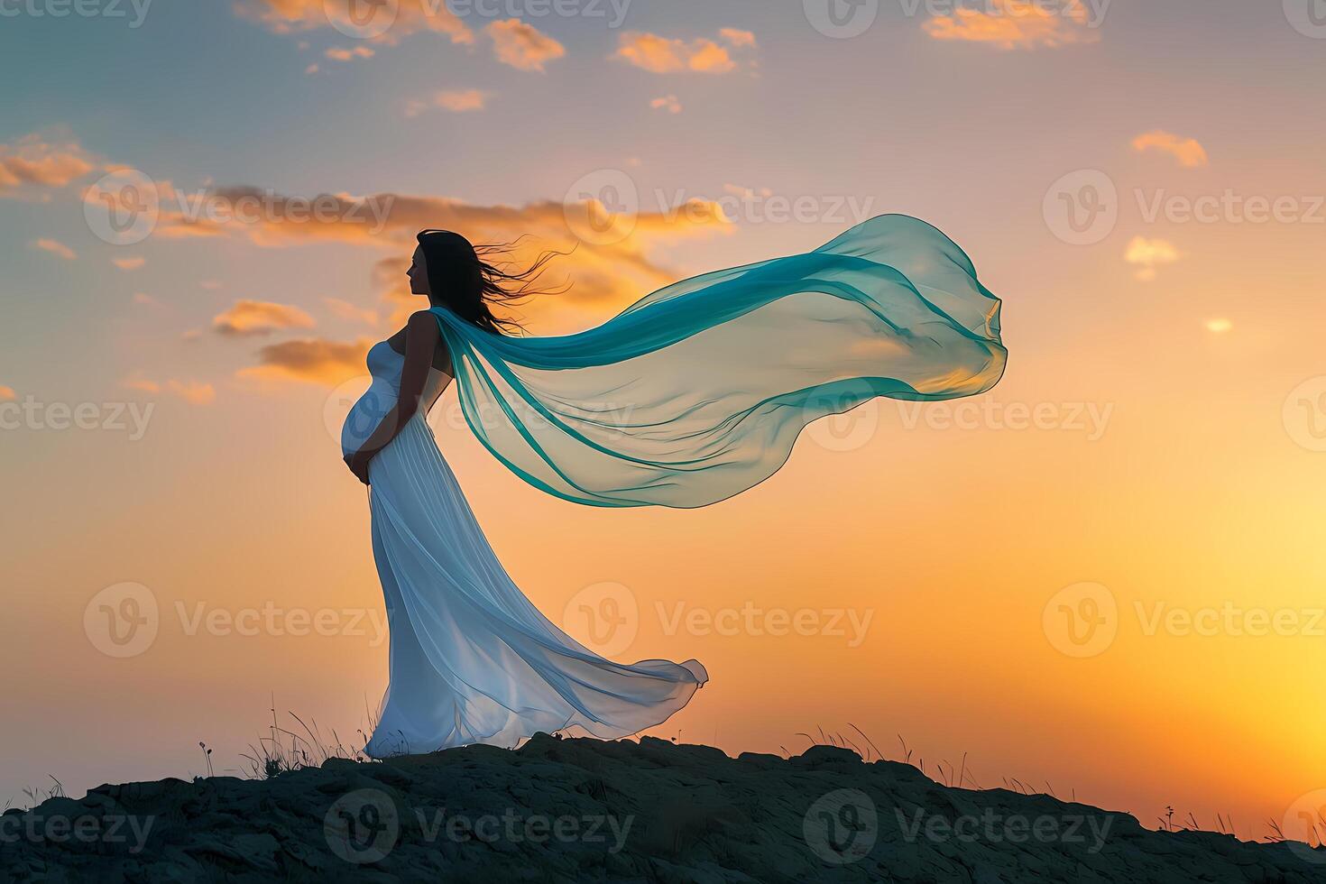 Pregnant woman embracing sunset on hilltop photo