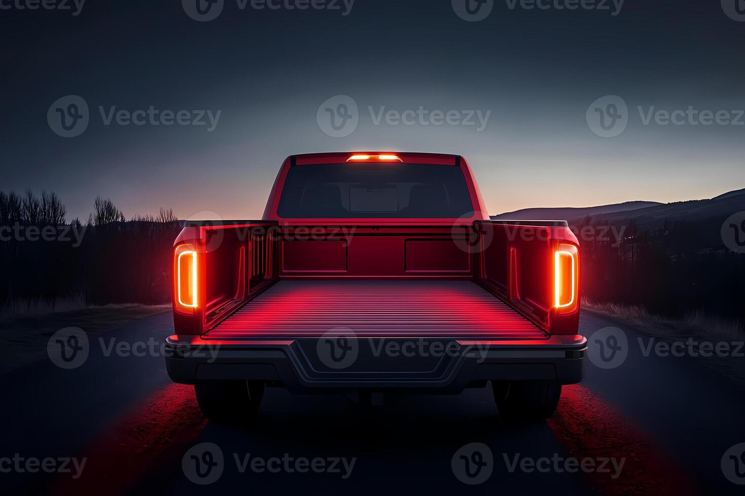 Red pickup truck parked on road at dusk with open trunk and illuminated cargo area photo