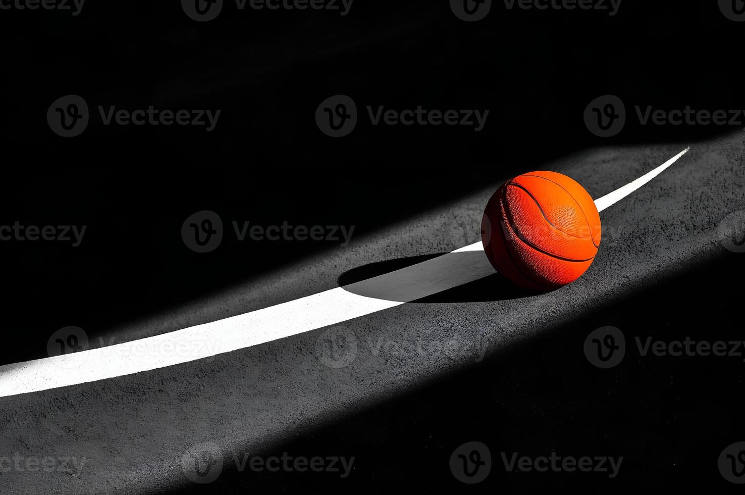 Basketball resting on court line in darkened gym with dramatic lighting photo