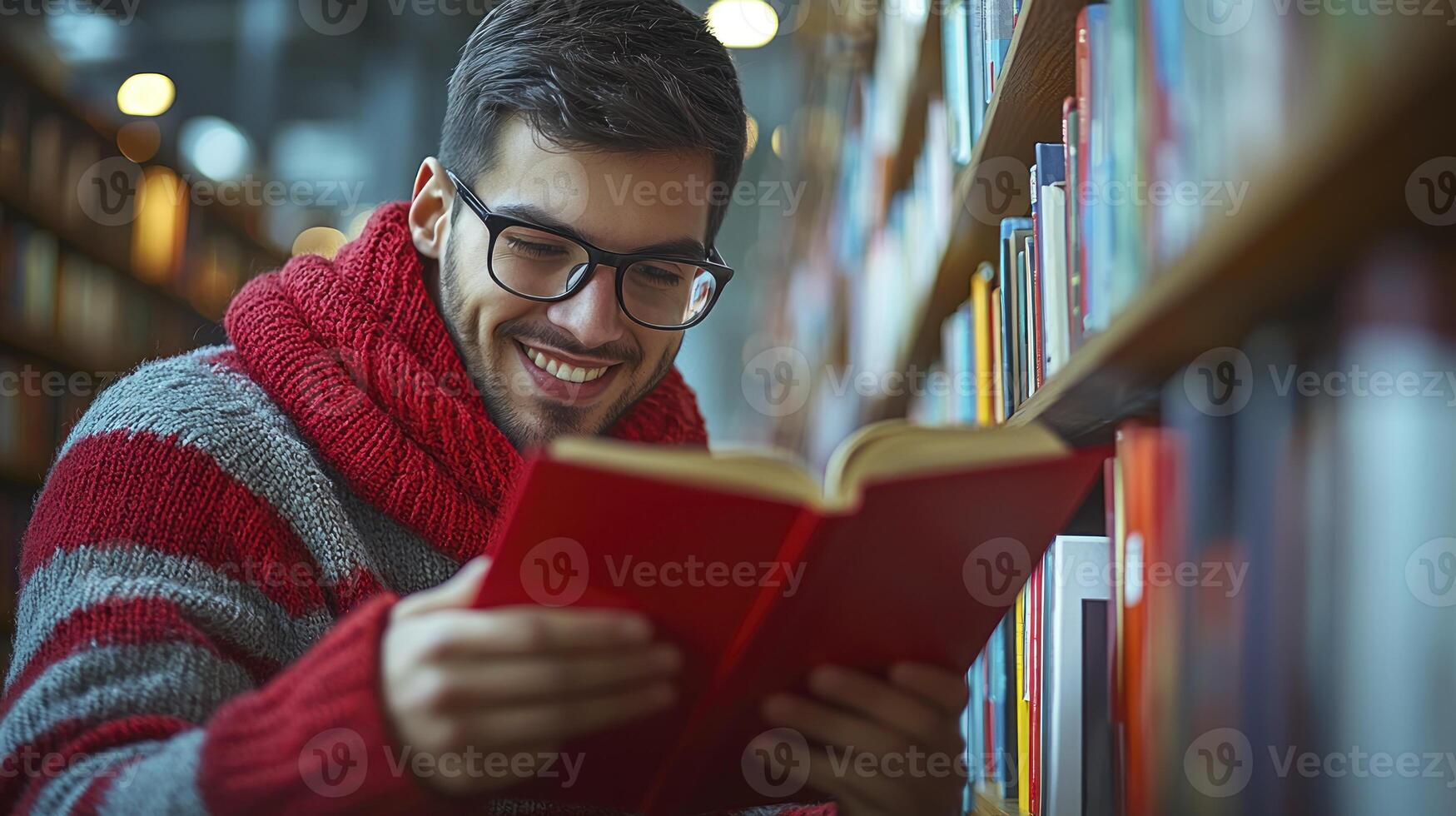 A man in glasses is reading a book in a library photo