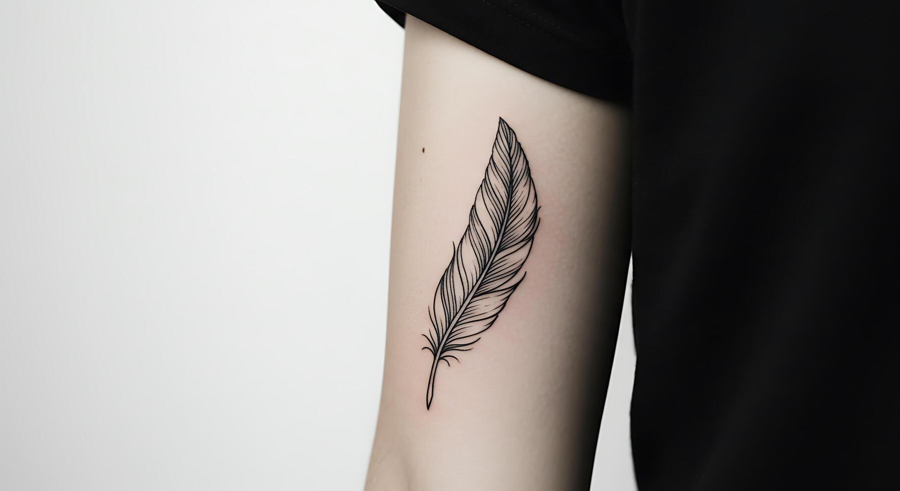 A black and white tattoo of a feather on the arm photo