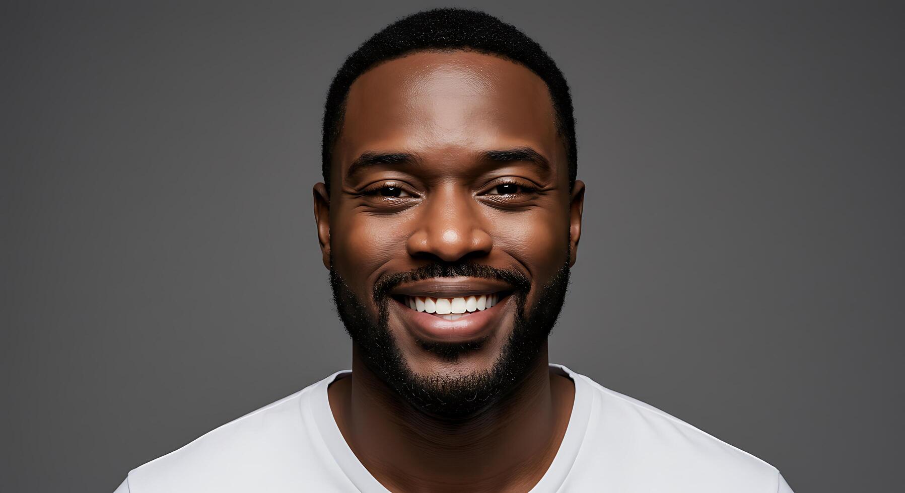 A black man smiling in a white t - shirt photo