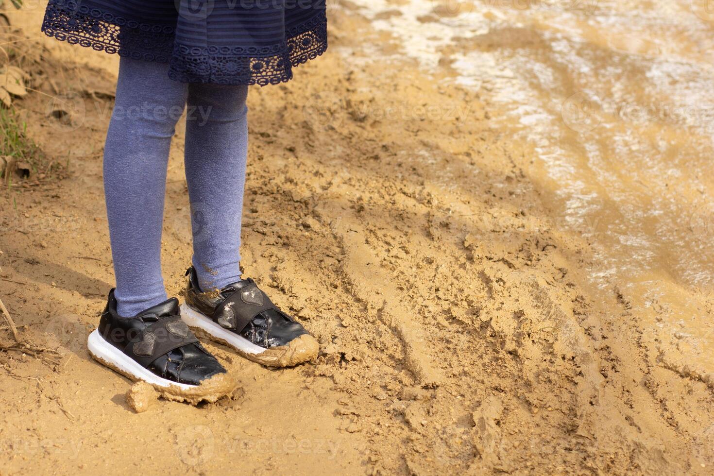 Child legs with shoes in mud outside on dirty roady photo