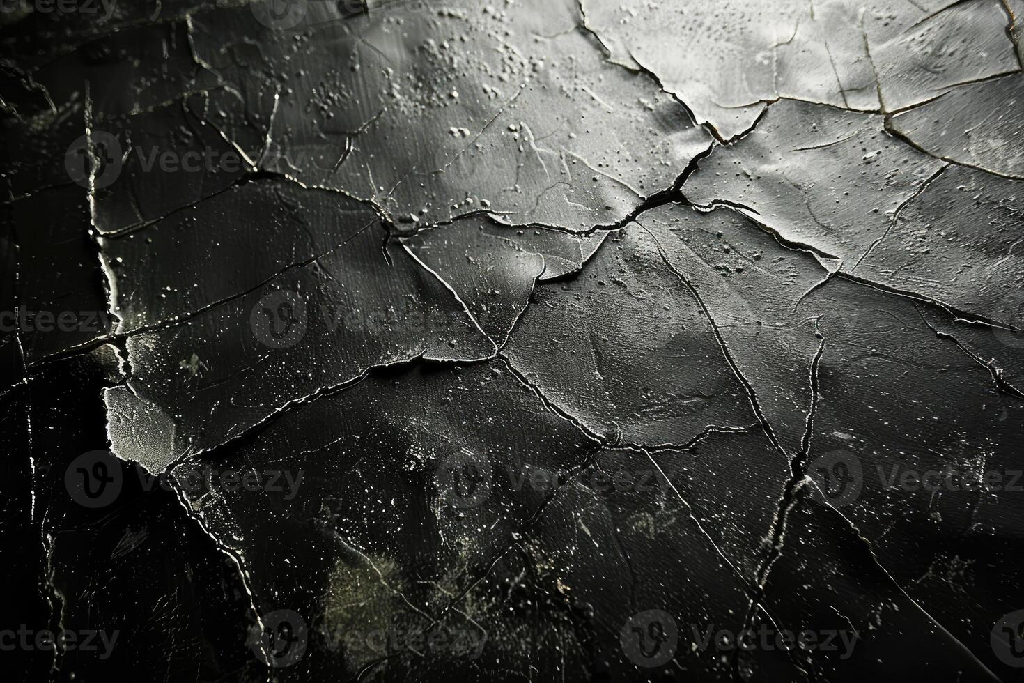 Dark, cracked surface texture of a weathered material. photo