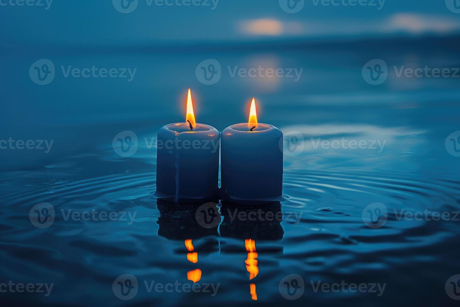 Two lit candles reflecting on calm surface of the water photo