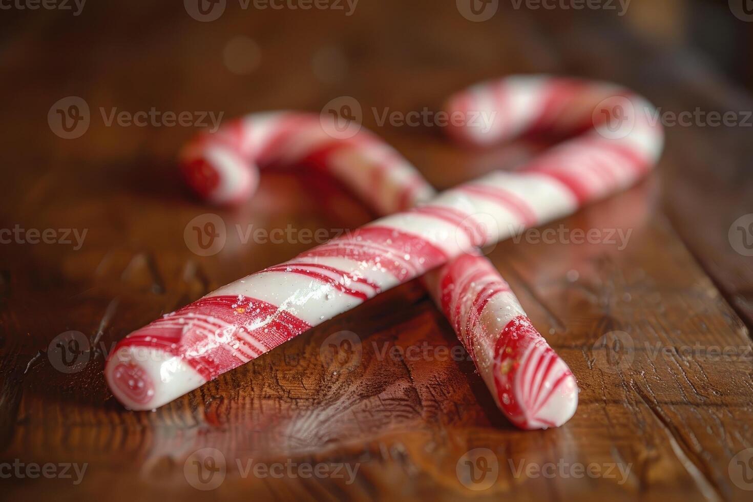 Two candy canes laying on a smooth wooden surface photo