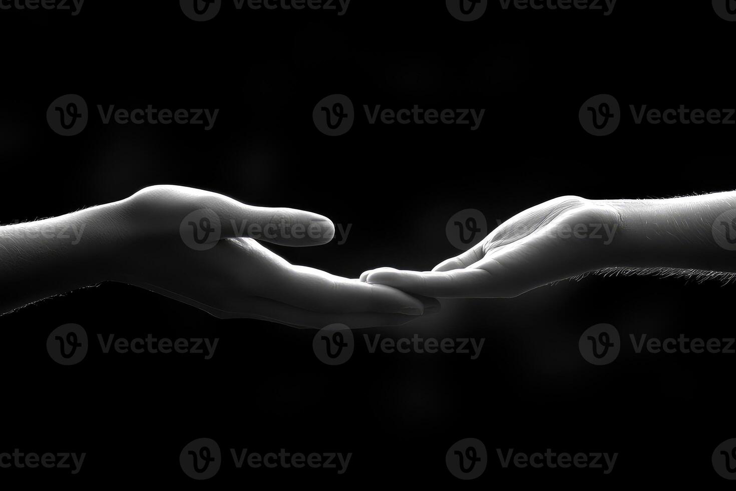 Two human hands gently reaching toward each other in darkness photo