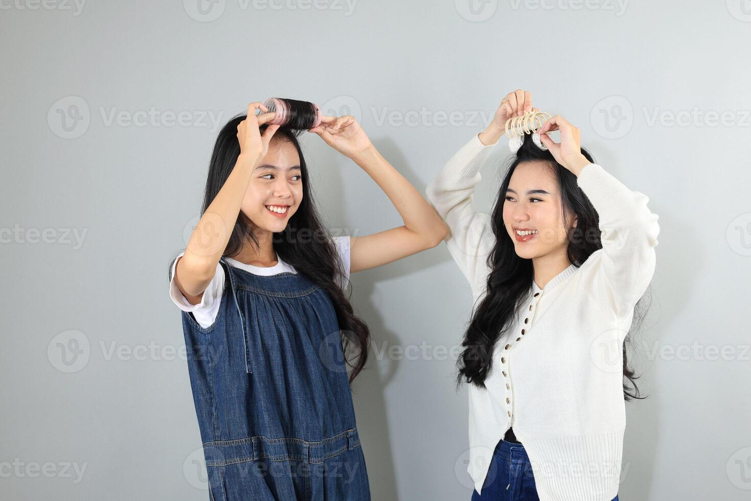 Two Young Asian Female Friend Smiling While Styling Hers Hair Bangs with Roller photo