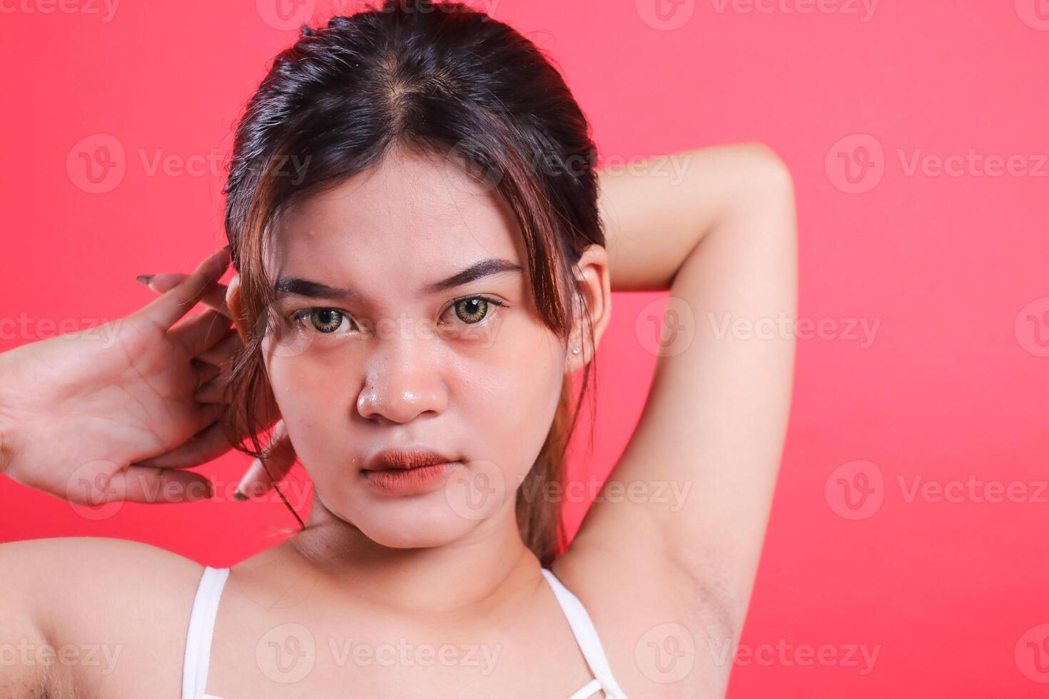 close up of woman indonesia wearing white top sports costume doing warm up looking at camera standing with both hands crossed behind head, isolated on red background photo