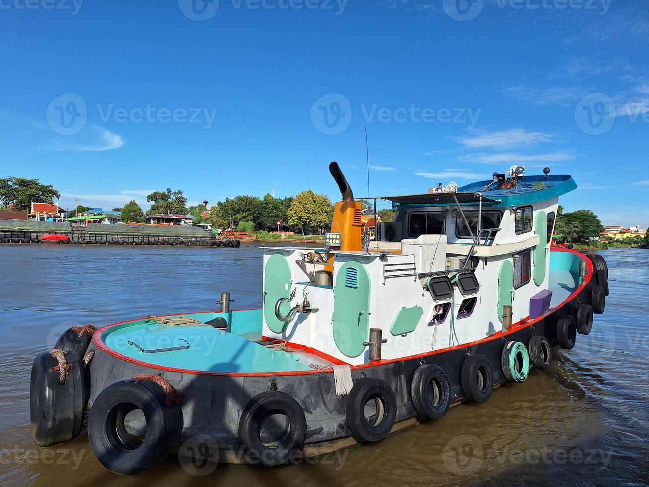 A tugboat sails along the Chao Phraya River with beautiful nature as a backdrop. photo