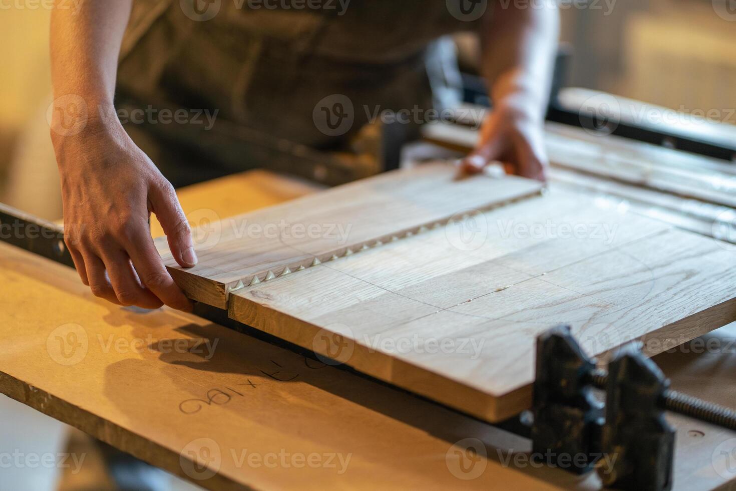 Joiner hands hold glued tabletop, clamp boards in one piece with clamps in furniture workshop photo