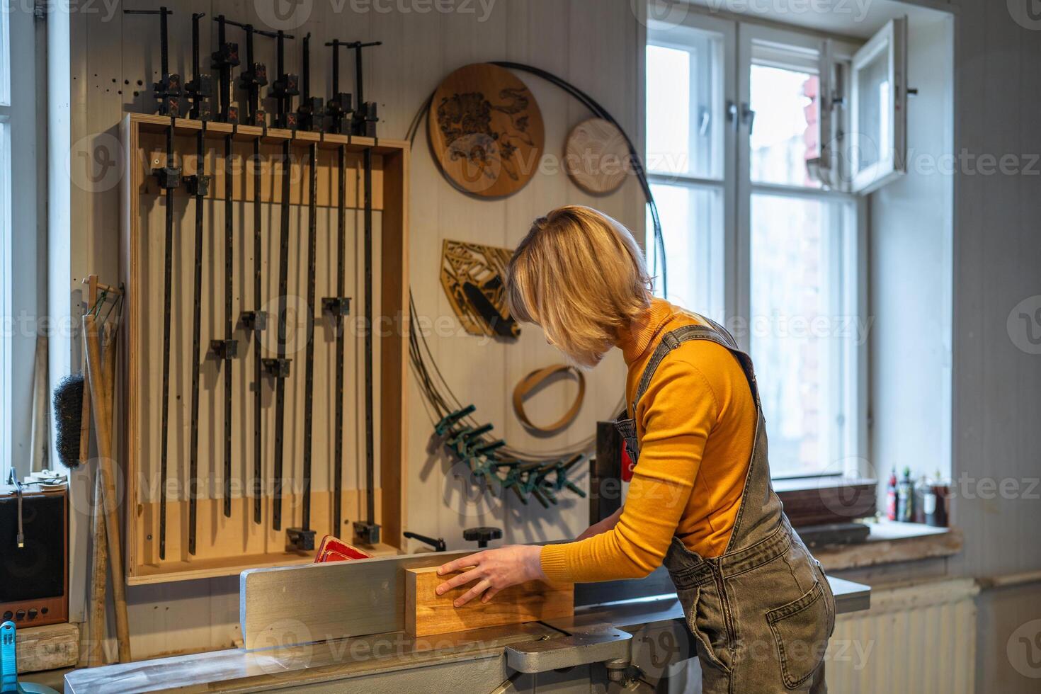 Woman carpenter operate table saw and electric planer, preparing wooden beams for future furniture photo