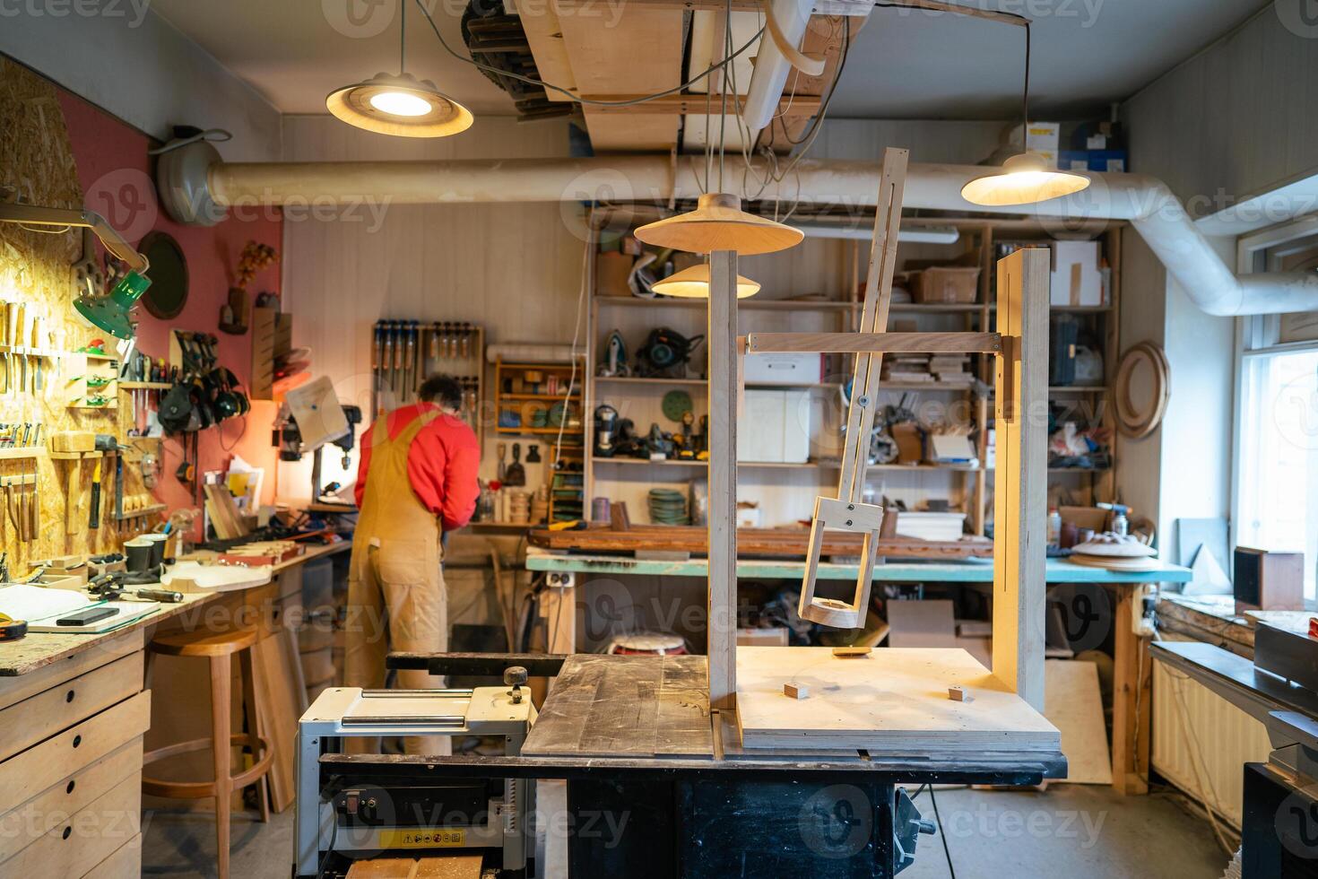 Rearview of busy carpenter preparing tools for woodworking in workshop, setting up machinery photo