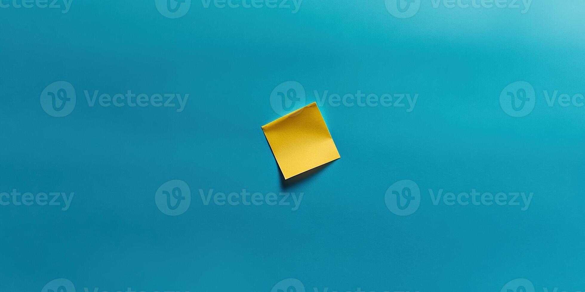 Minimalist top down composition of a blank yellow sticky note on a blue background photo
