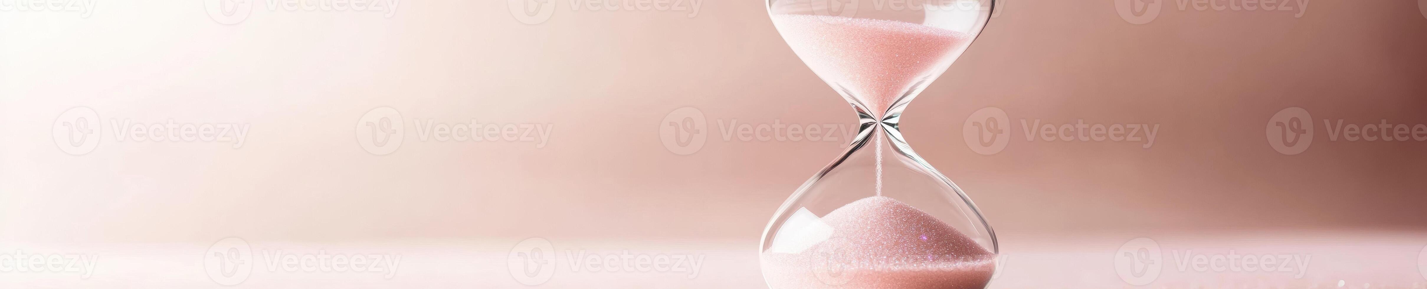Elegant hourglass with pink sparkle sands on soft pastel background photo