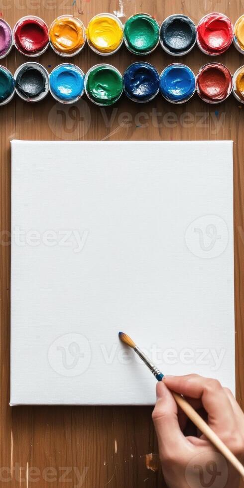 Artist perspective. Preparing to paint on a blank canvas with colorful paints photo