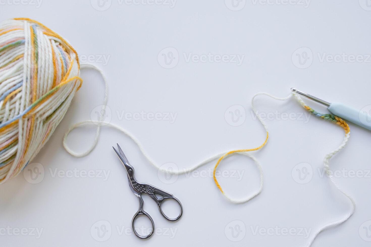 Colorful yarn ball with crochet hook and scissors on white background. photo
