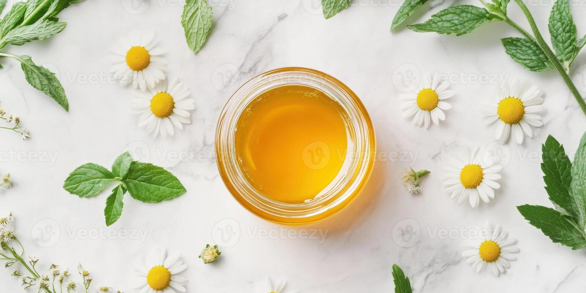 Flat lay of golden honey jar with fresh chamomile and mint leaves on marble surface photo