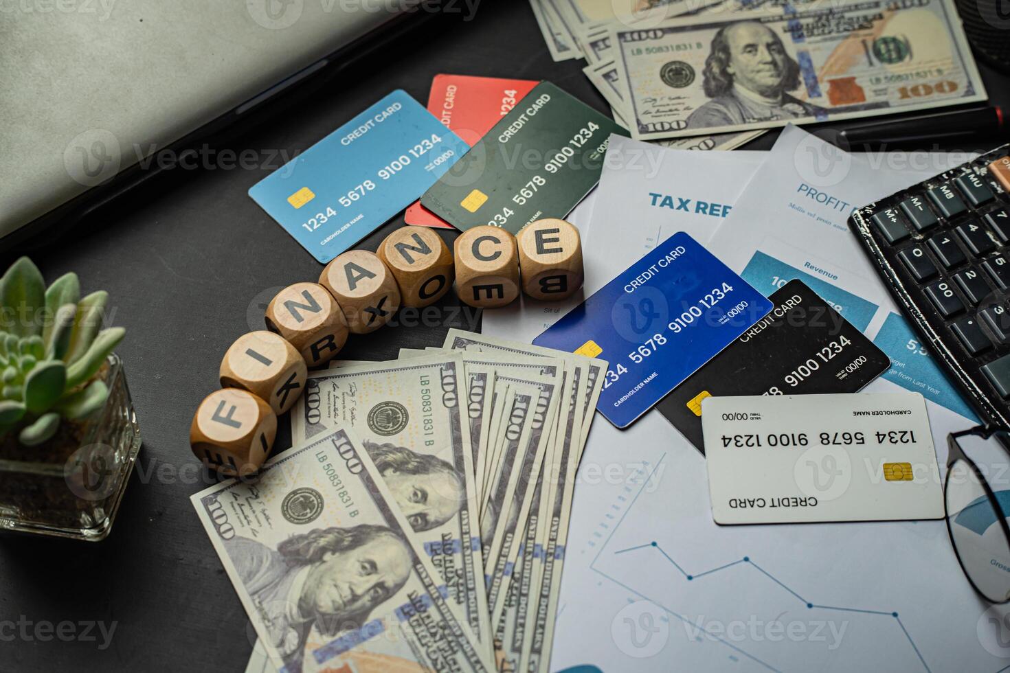 Business and finance background image showing a blend of paper currency, credit cards, profit charts, tax files, and an office setup. The word FINANCE arranged with wooden letter blocks photo