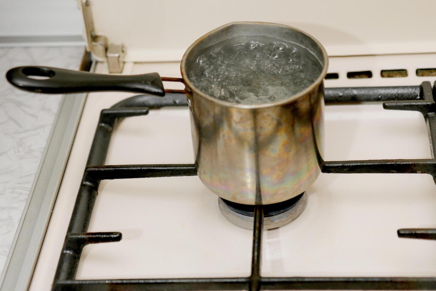 a ladle of boiling water on a gas stove photo