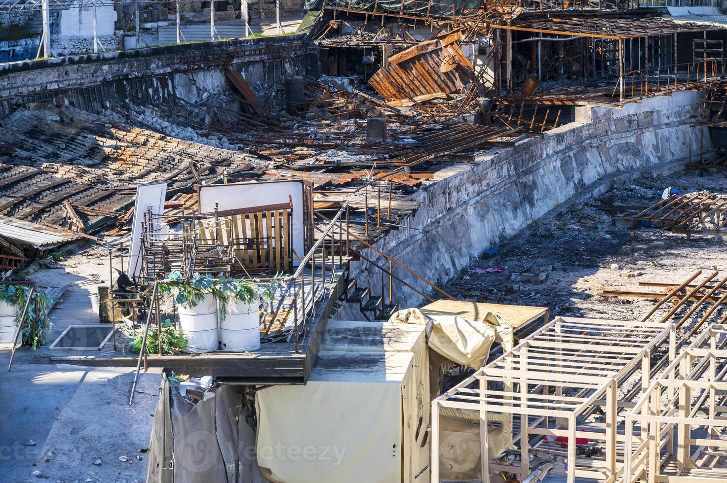 Damaged buildings after a fire. consequences of a fire in the city. Burnt metal structures. Burnt buildings of a restaurant, cafe or shopping center. restoration work is underway in the foreground photo