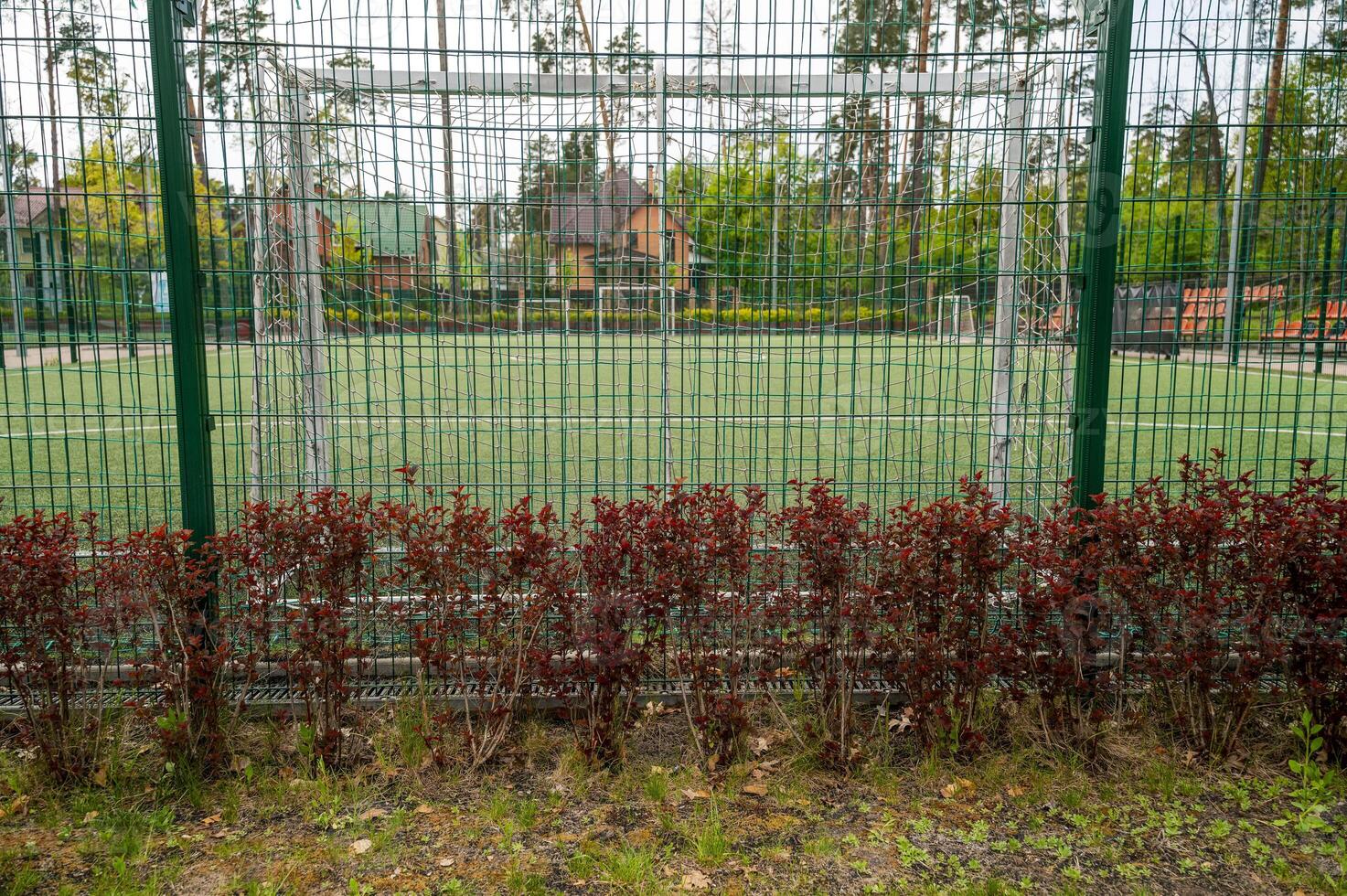 soccer field behind the fence, football field with goals and white lines on the grass, surrounded by a green net, a fence around a football field in the form of an iron net with large cells. photo