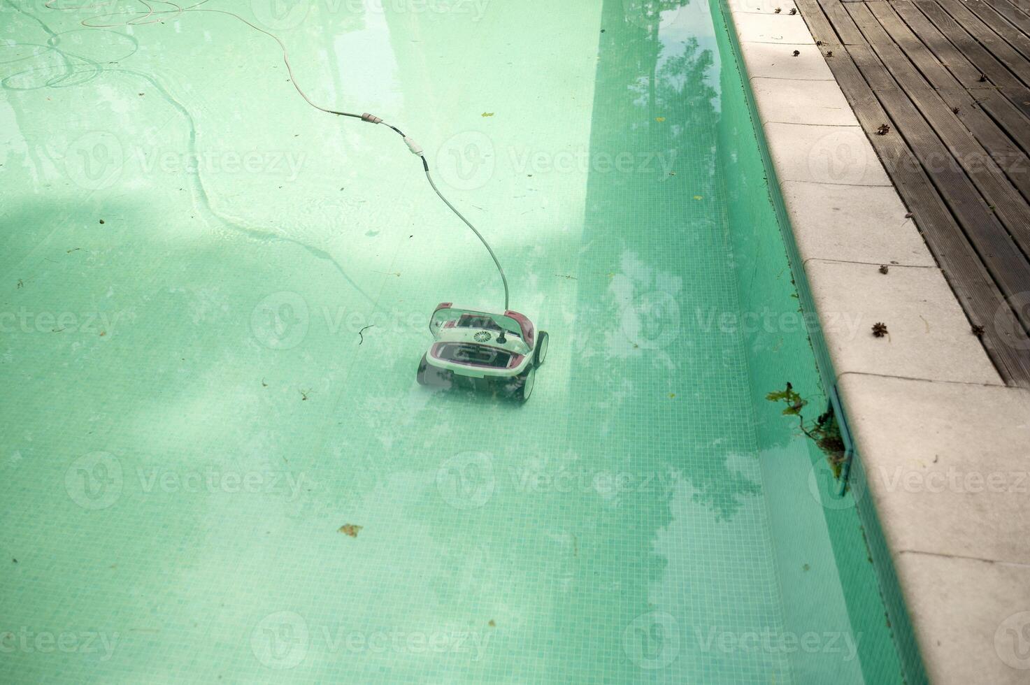 Water robot vacuum cleaner cleans, removes debris on the bottom, walls of the pool, top view through translucent water. Pool cleaning process. Preparing for the summer season. Smart home technologie photo