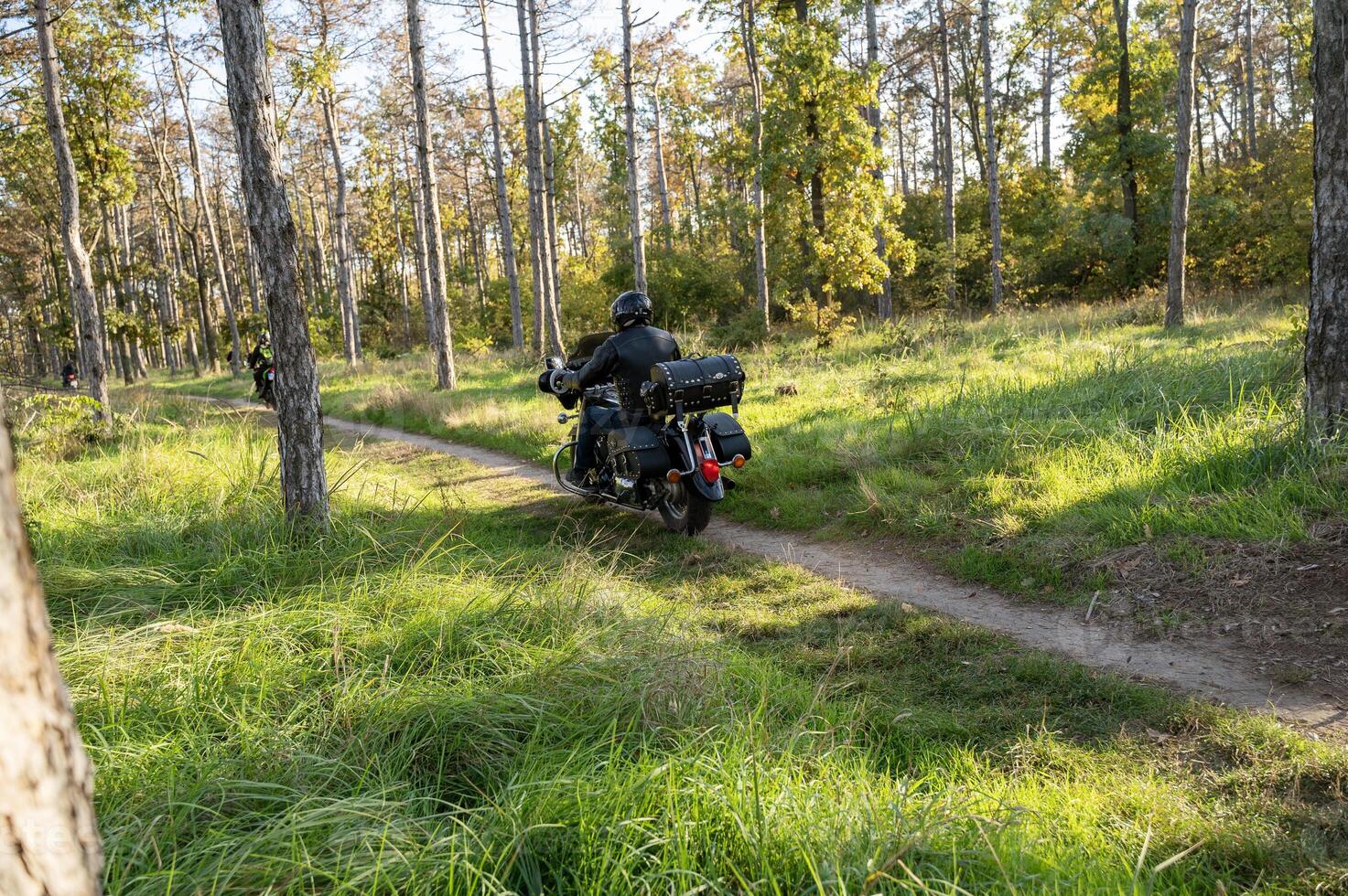 A man riding a motorcycle on a trail through a forest photo