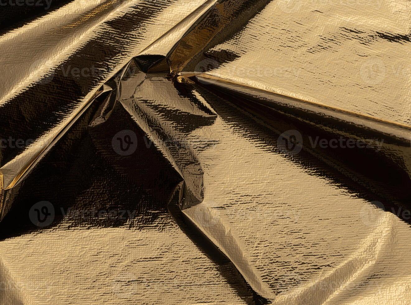 Golden foil reflective folds with a shiny, metallic finish. Luxurious, crumpled texture creating a photo