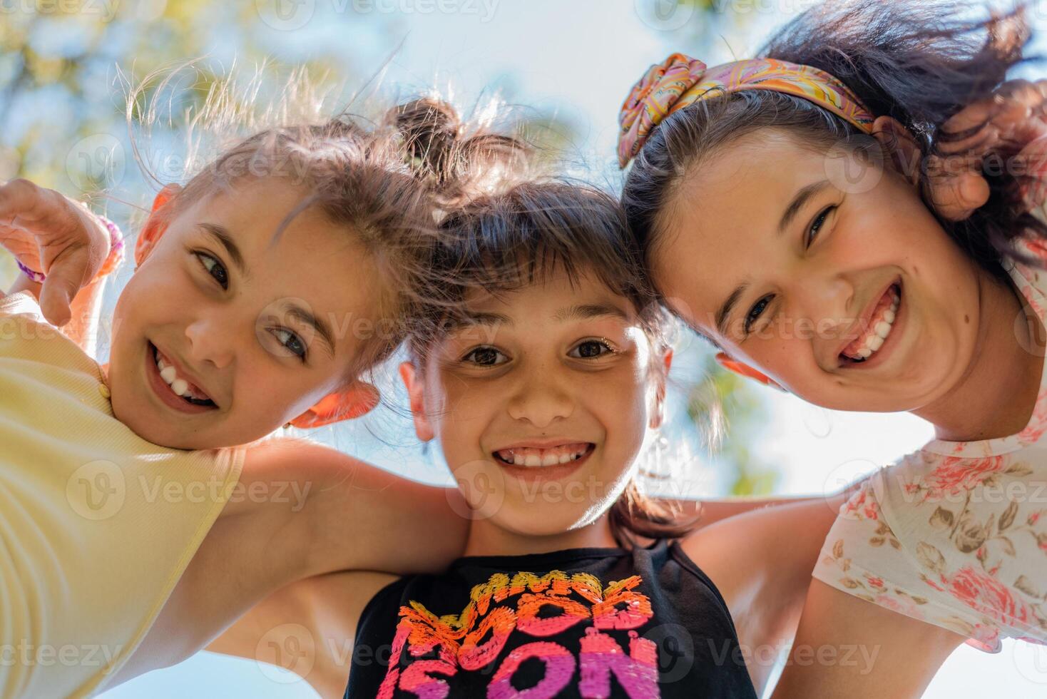 Close up face of happy children embracing each other and smiling at camera, group of joyful kids playing together outside. photo