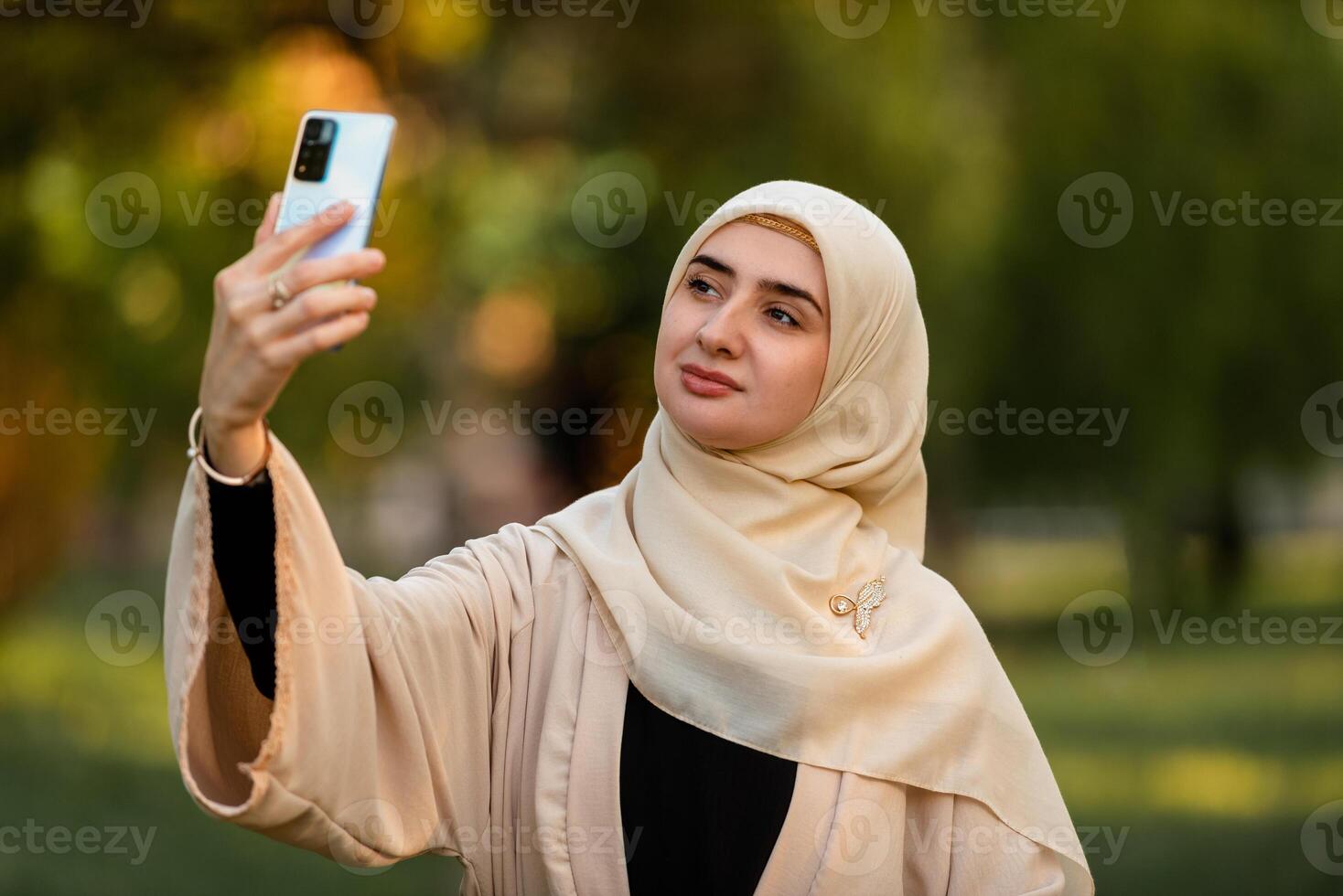 A young happy muslim woman in hijab taking a selfie outside. photo