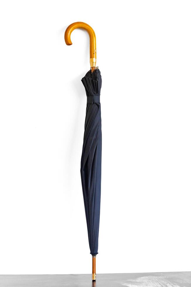 Typical black umbrella closed and isolated on white background isolated photo