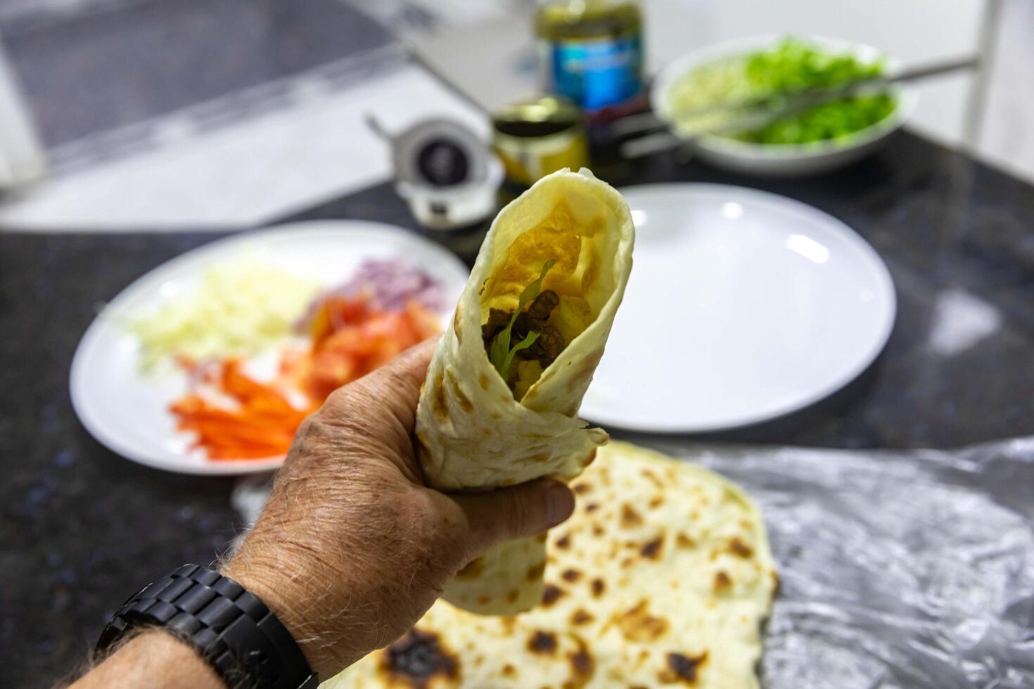 The most traditional and classic shawarma prepared in Syrian bread or pita bread grilled on a stone on hand photo