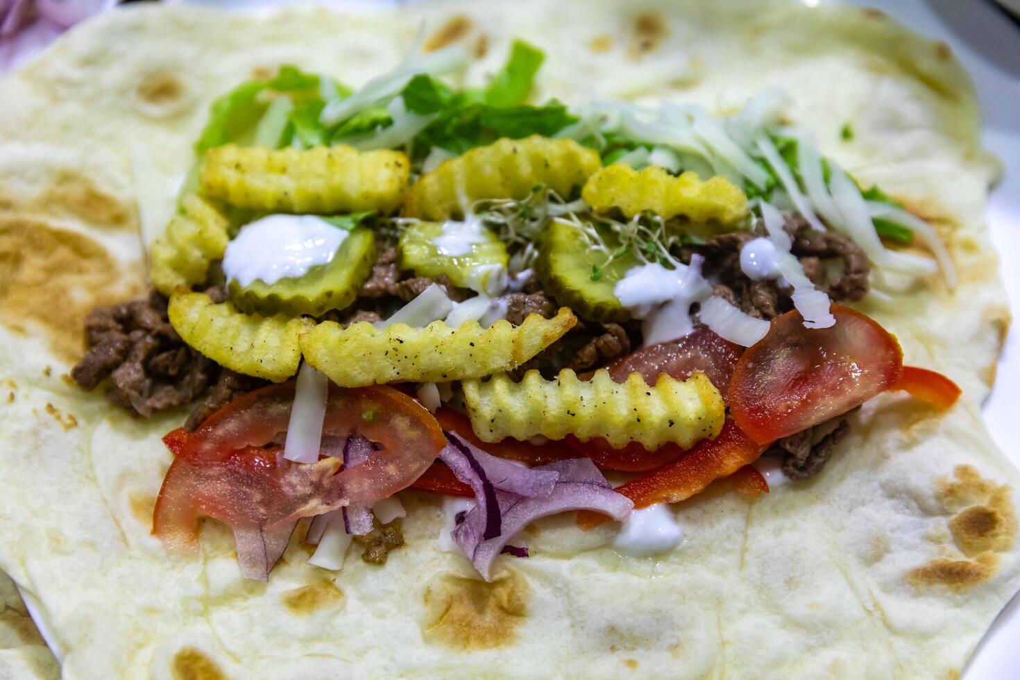 The most traditional and classic shawarma prepared in Syrian bread or pita bread grilled on a stone top view photo