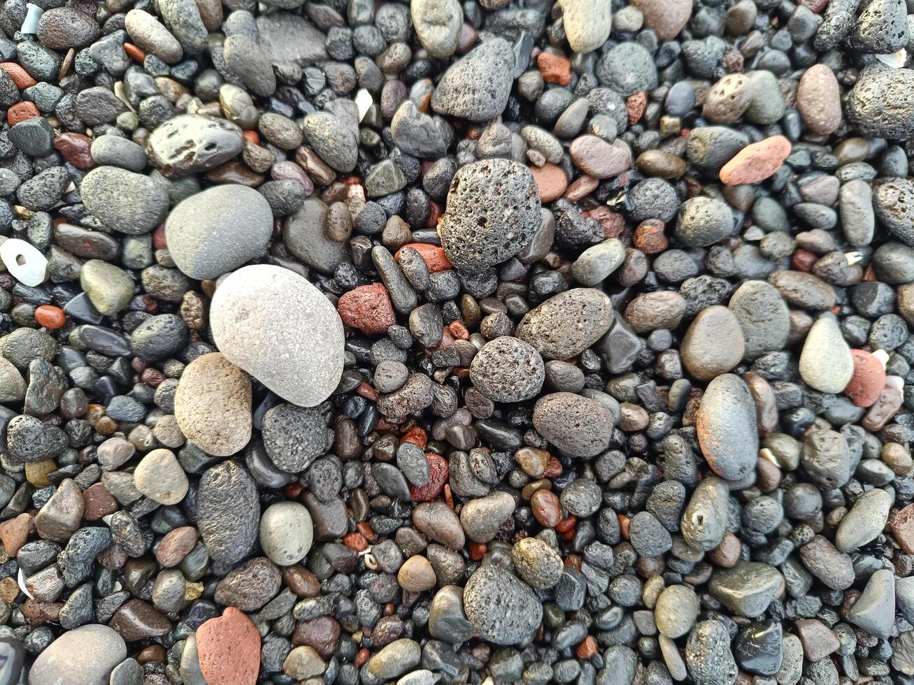 Close up photo of colorful and various shaped beach pebbles on a beach in Bali, for background