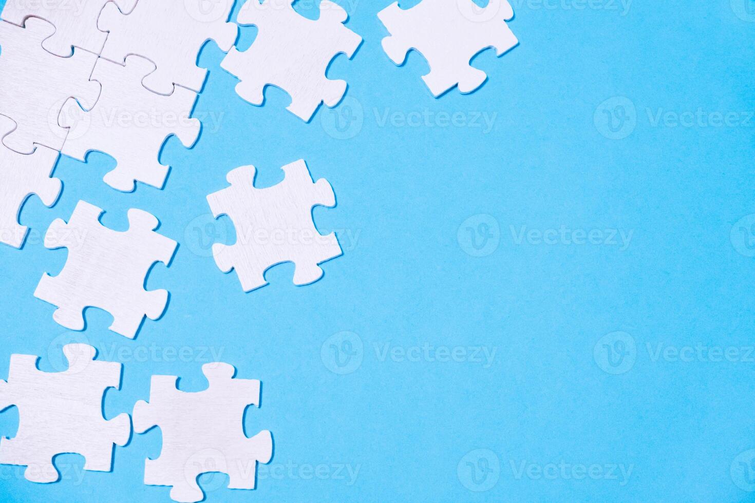 Blue background with white puzzle pieces scattered across it. photo