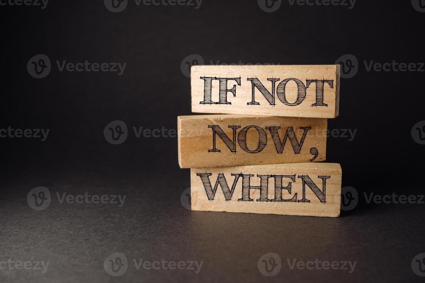 Three wooden blocks with the words if not now when written on them photo