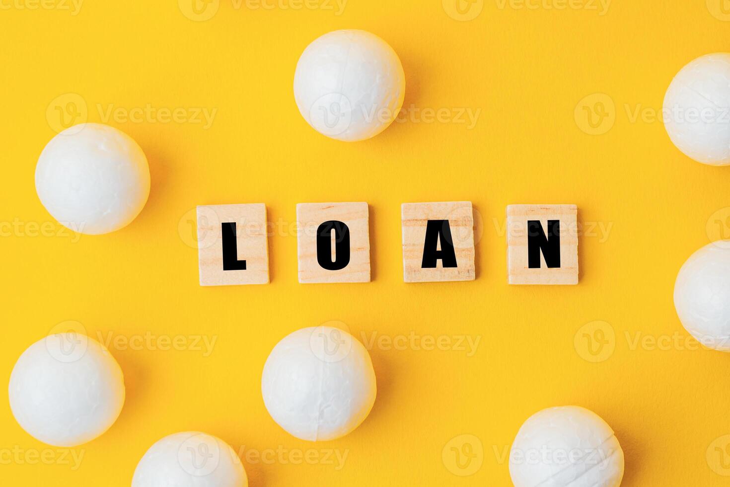 A yellow background with white balls and the word loan written in black photo