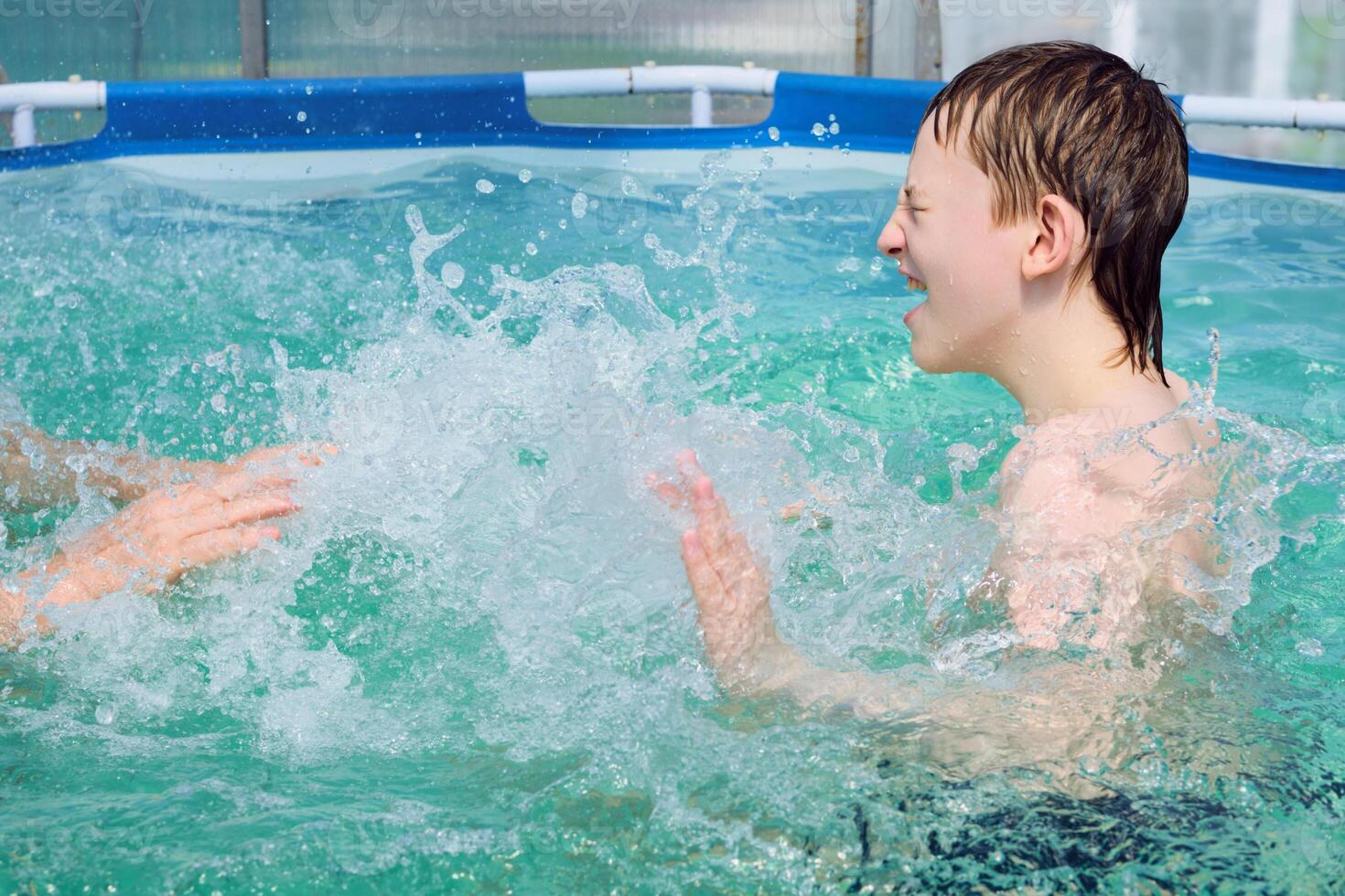 boy splashing on summer pool having fun activity photo