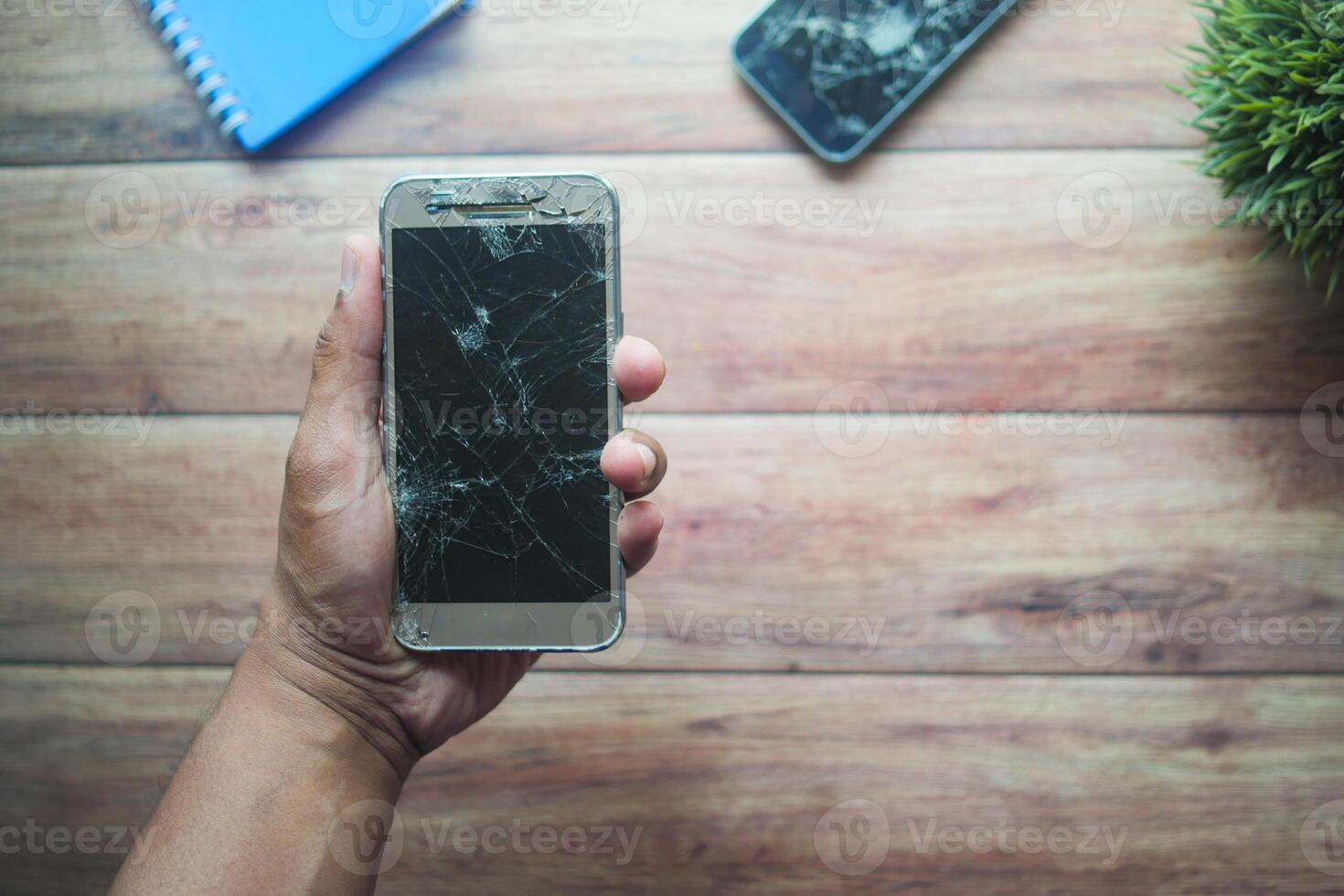 Broken smartphone held in hand on wooden table photo