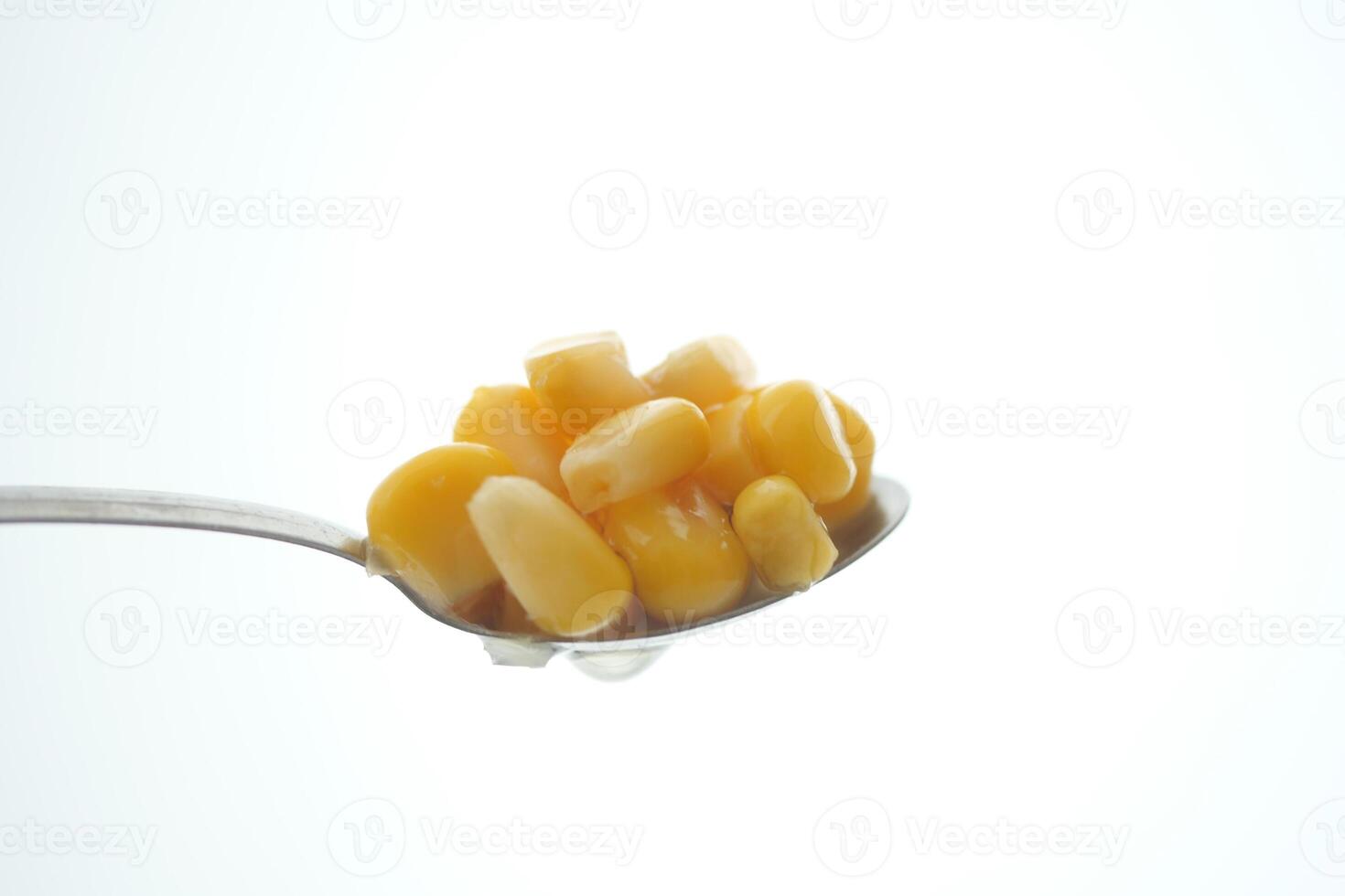 Close-up of corn kernels on a spoon against a bright background photo