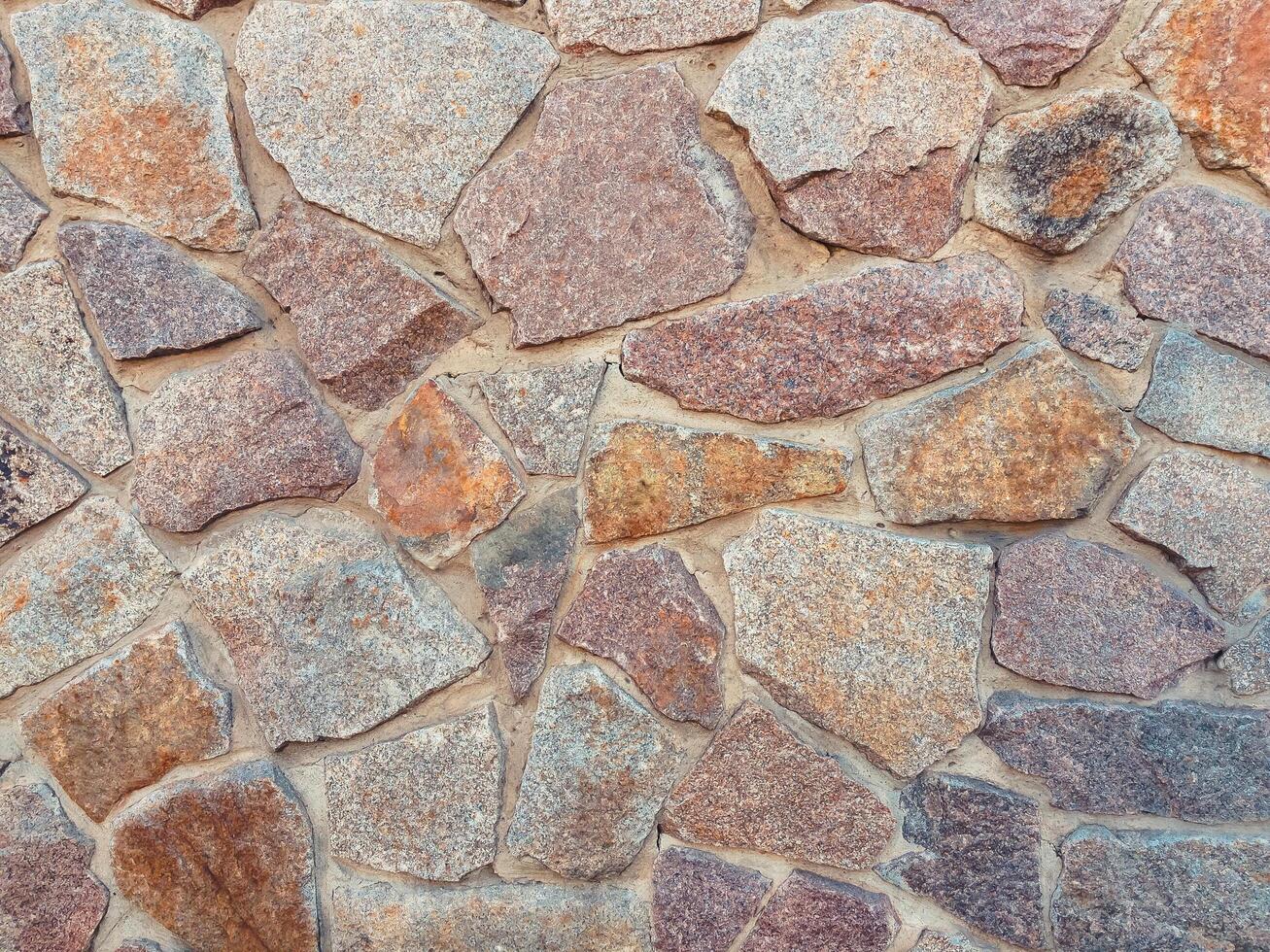 Wall made of stone with a pattern of different colored stones photo