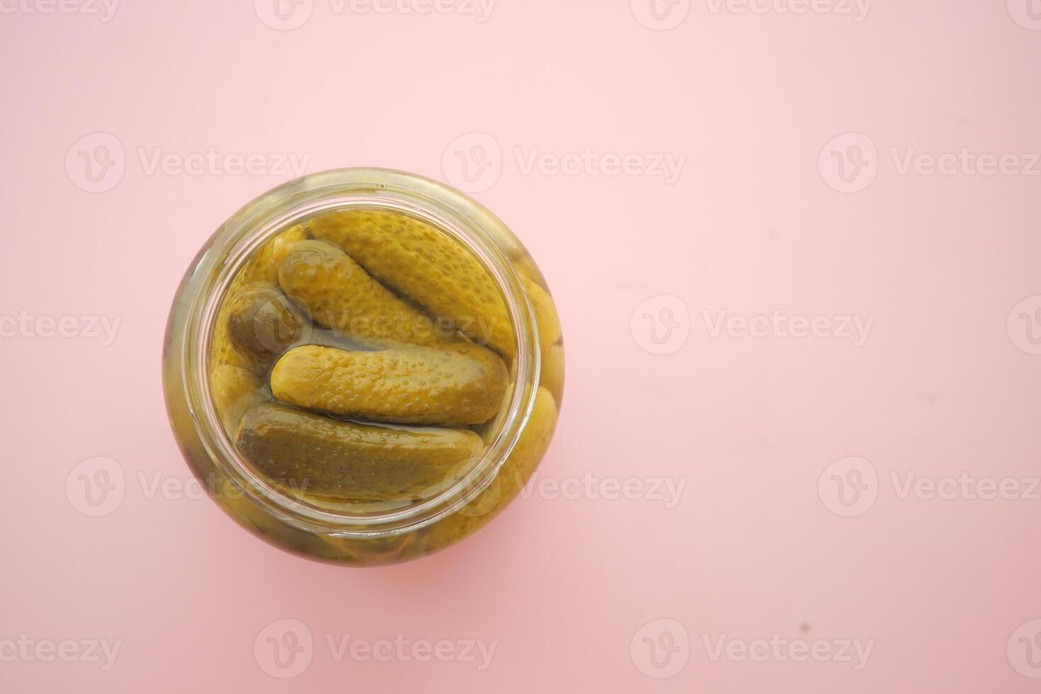 Pickles in a jar on pink surface photo