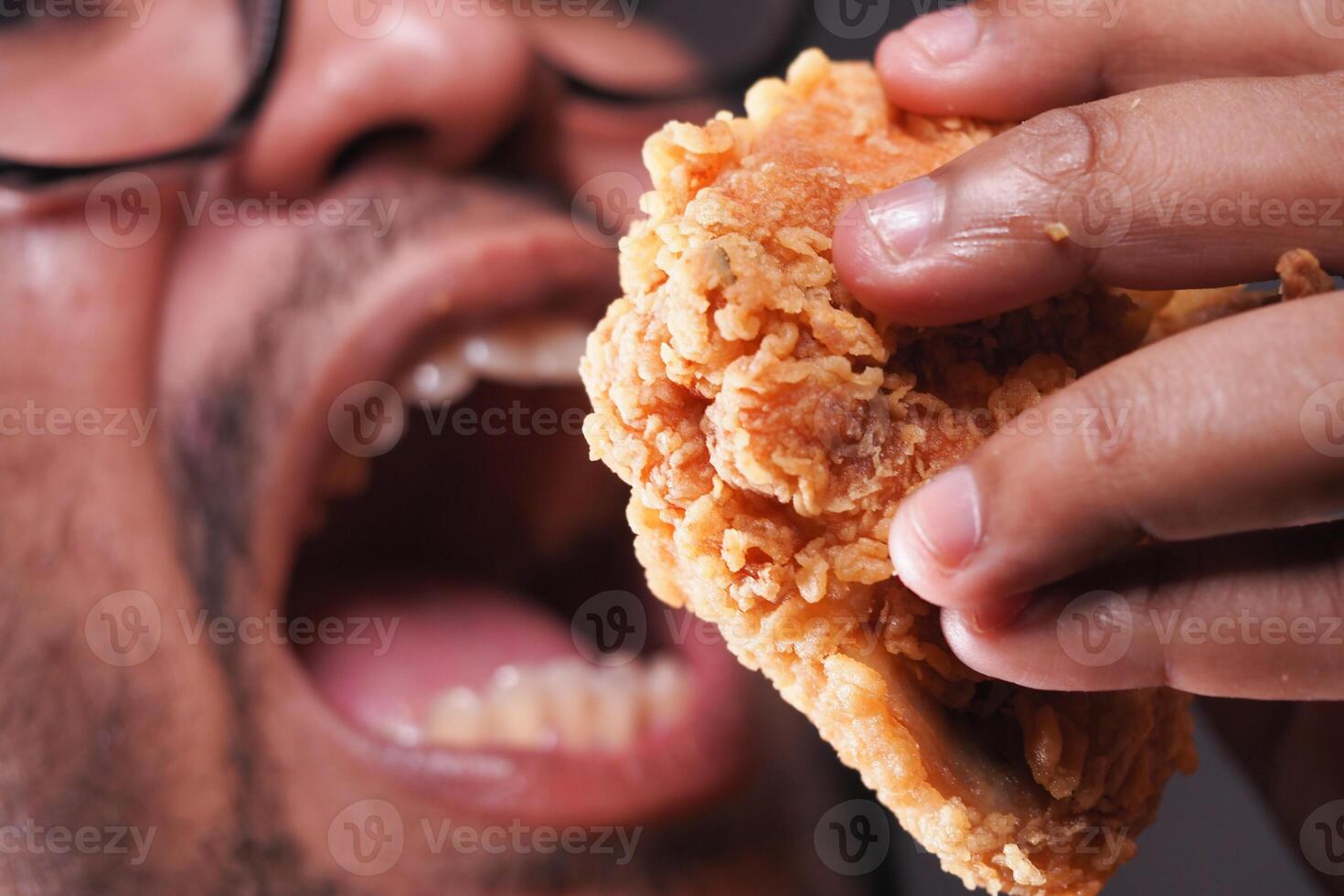 Person enjoying crispy fried chicken in close-up shot photo