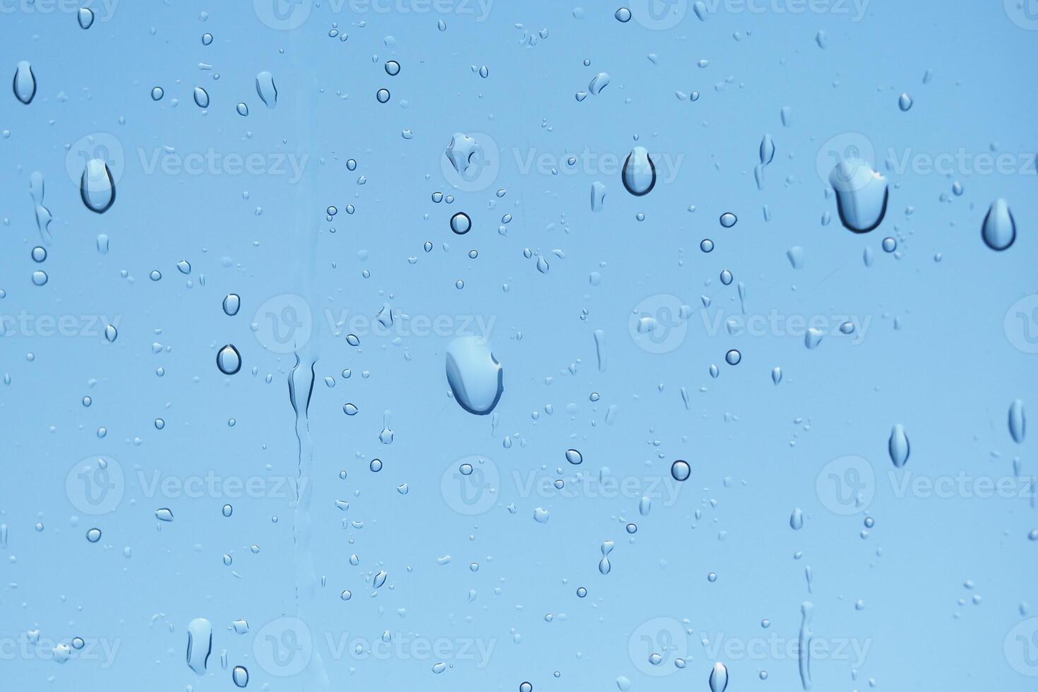 Raindrops on glass against a clear blue sky in daylight photo