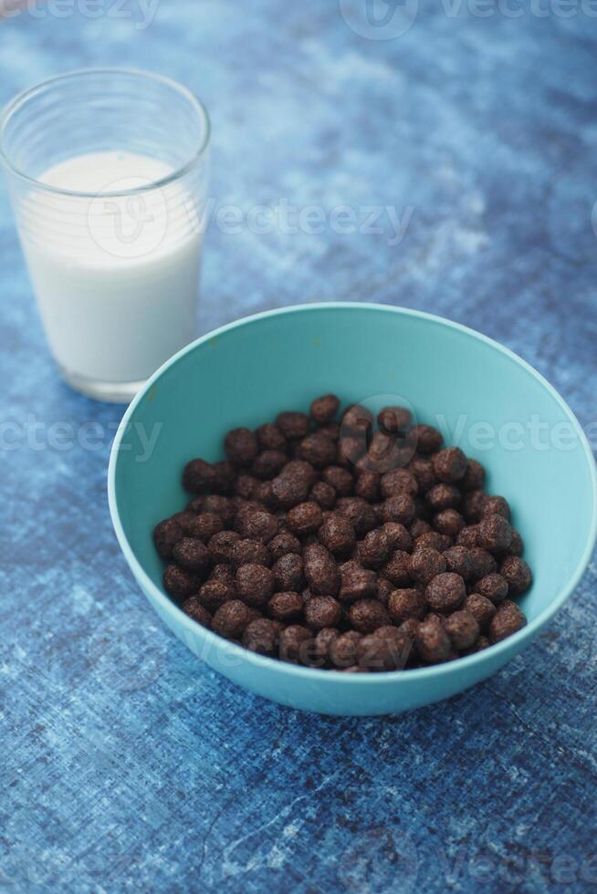 Chocolate cereal in a blue bowl with milk on a blue background photo