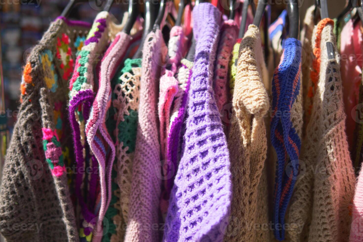 Colorful knitted garments displayed at a market stall in sunlight photo