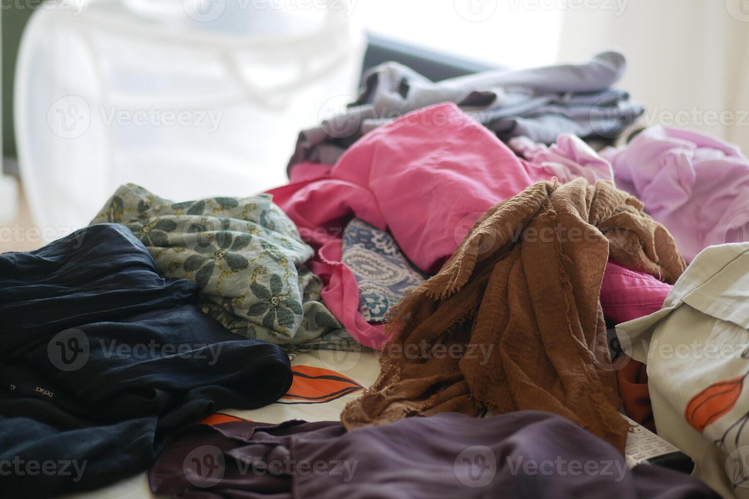Clothes piled on a table in a bright room during the day photo