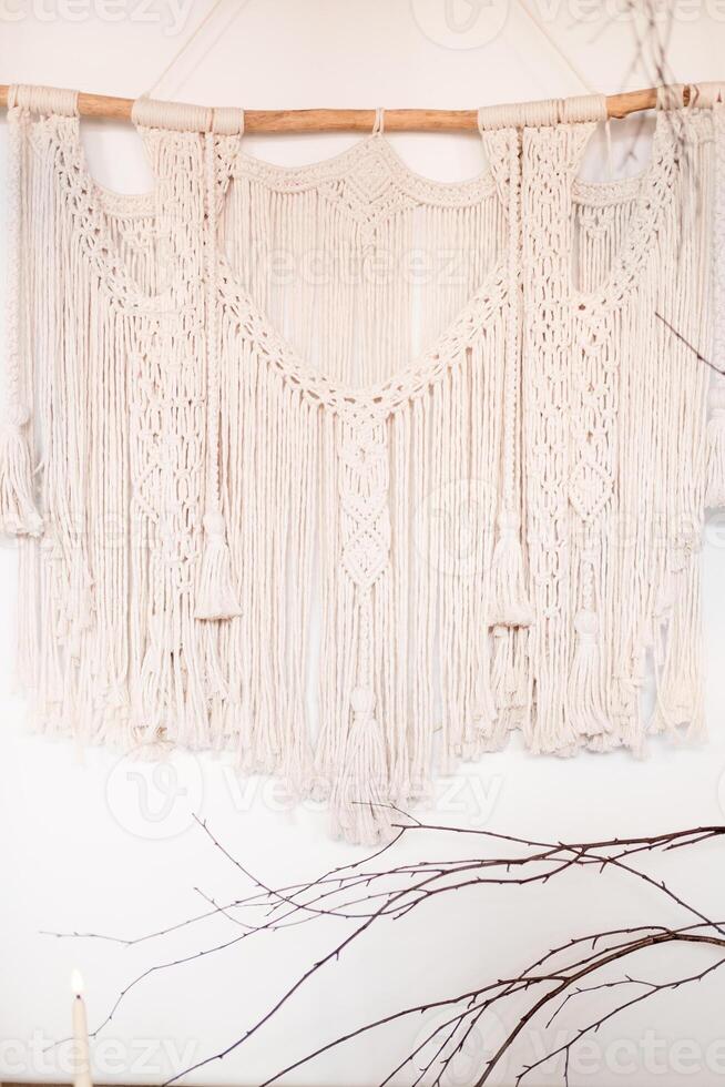 wall macrame with wooden stick hanging on white wall at home photo
